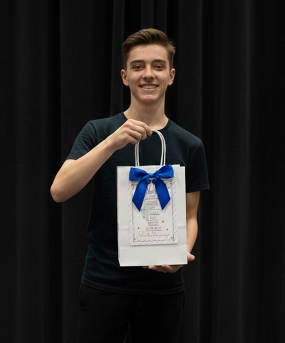 Person holding Dance Competition Survival Kit with a blue bow against a black background